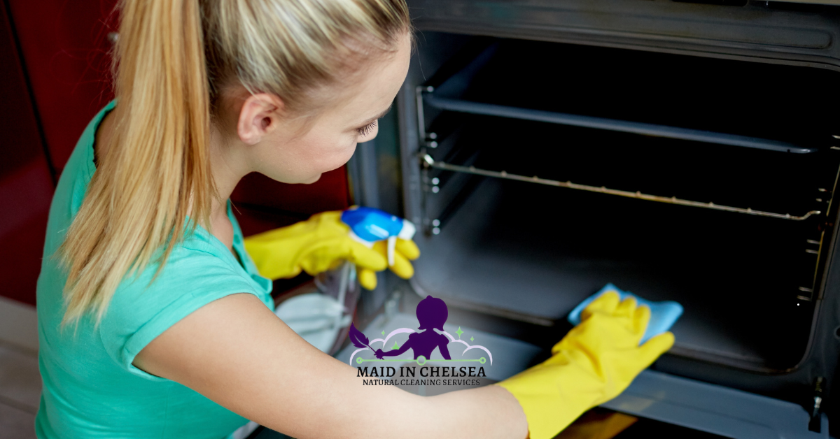 image of a professional cleaner, cleaning the oven with a spray and scrub